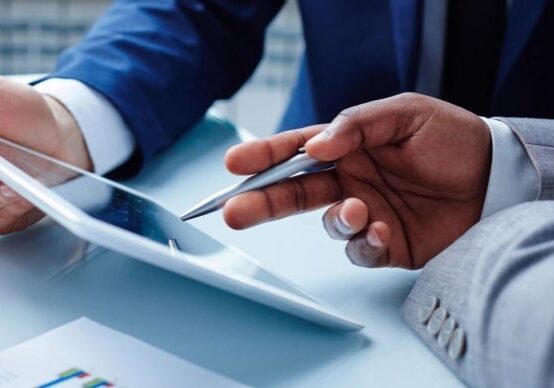 A person holding a cell phone and looking at an ipad.